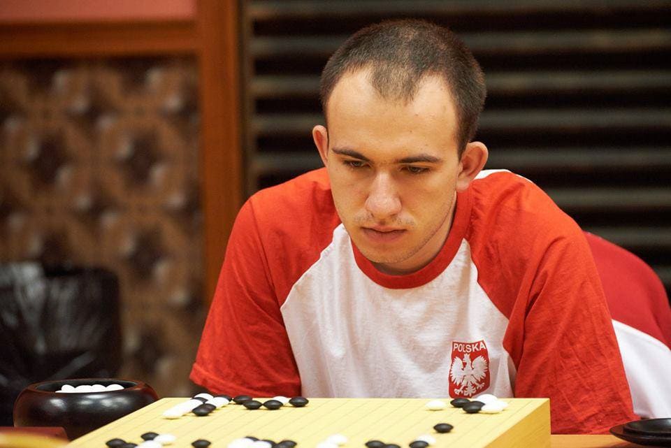 Mateusz Surma in deep concentration during an intense Go match against Korean player Kim Sungjun, wearing the Polish national team jersey.