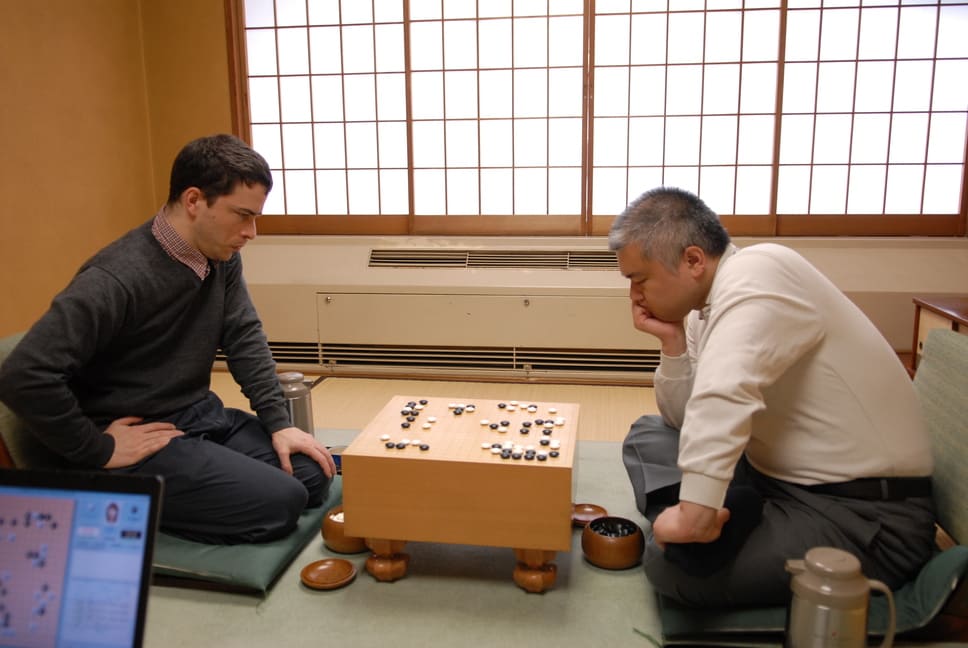 Michael Redmond focused on a Go match against Yoda Norimoto in a traditional Japanese setting.