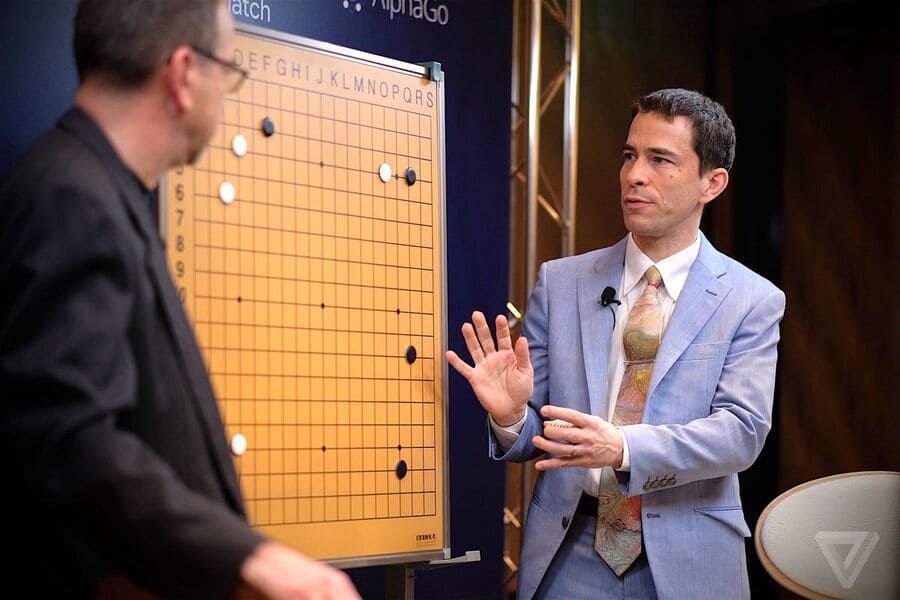 Michael Redmond providing expert commentary during a professional Go match, explaining strategies on a demonstration board.