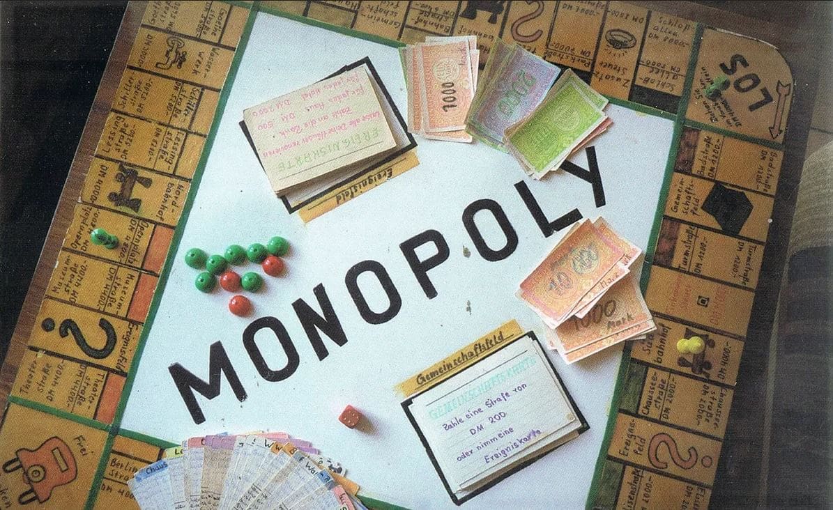 A homemade Monopoly board with custom cards and currency laid out for play.