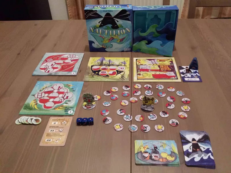 Nautilion board game displayed with tokens, dice, boards, and a whimsical ocean-themed box on a table.