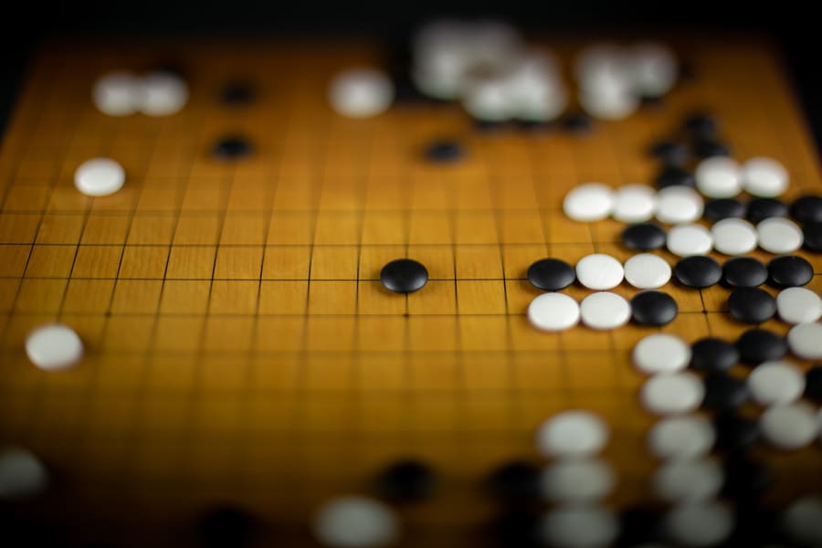 A close-up of a traditional wooden Go board with black and white stones placed in strategic positions, highlighting the beauty of the game.