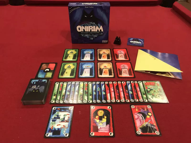 Onirim card game spread on a table, featuring colorful cards, tokens, and the box, ready for play.