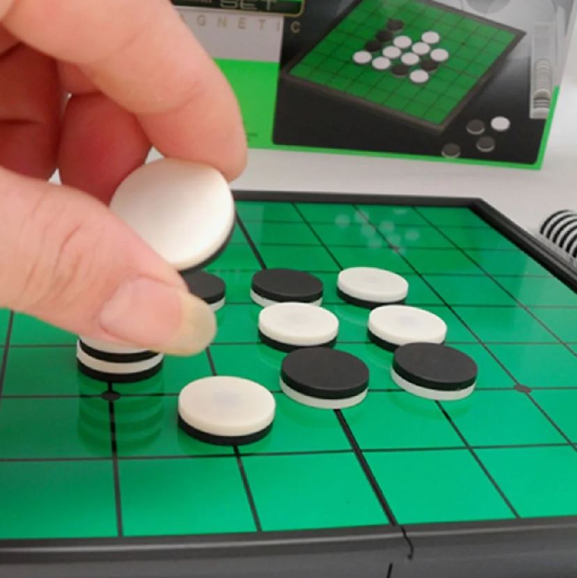 A close-up of a hand placing a piece on an Othello board.