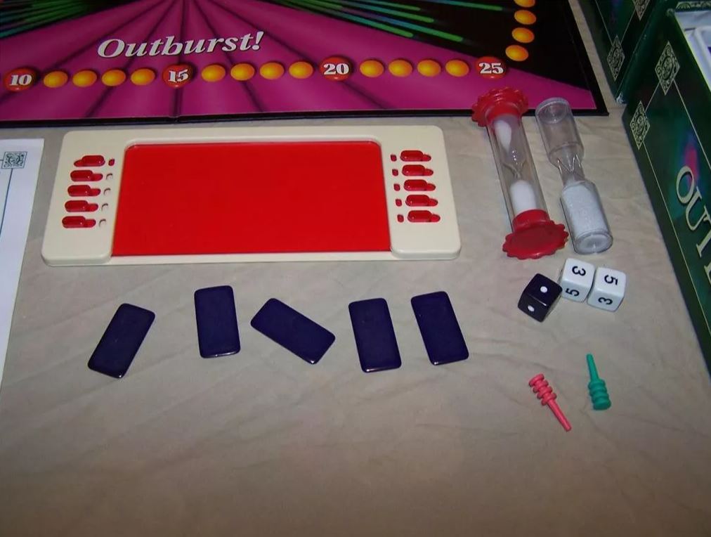 Outburst game setup showing dice, a timer, player tokens, and the game board with scoring sections, prepared for a competitive trivia challenge.