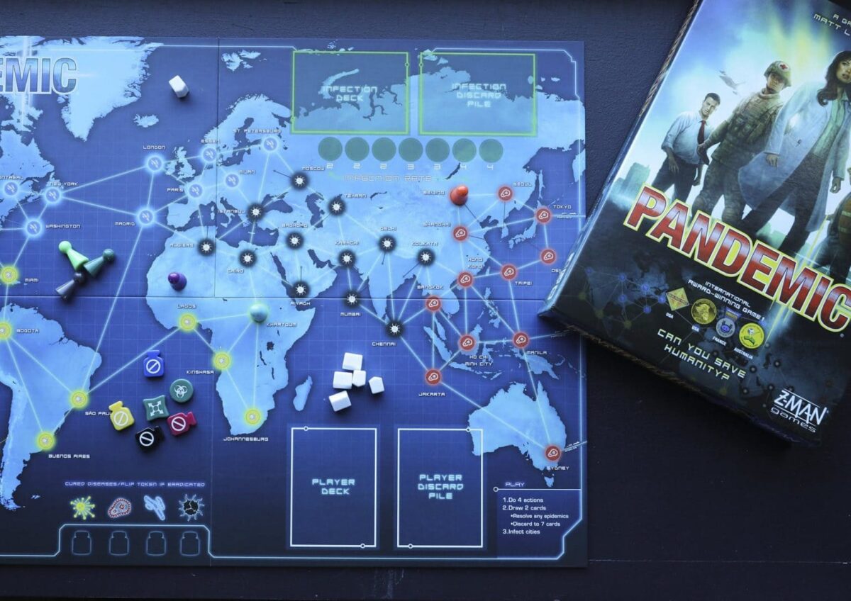 A setup of the Pandemic board game, showing the world map, game pieces, and cards, with the game box on the side, ready for solo or cooperative play.