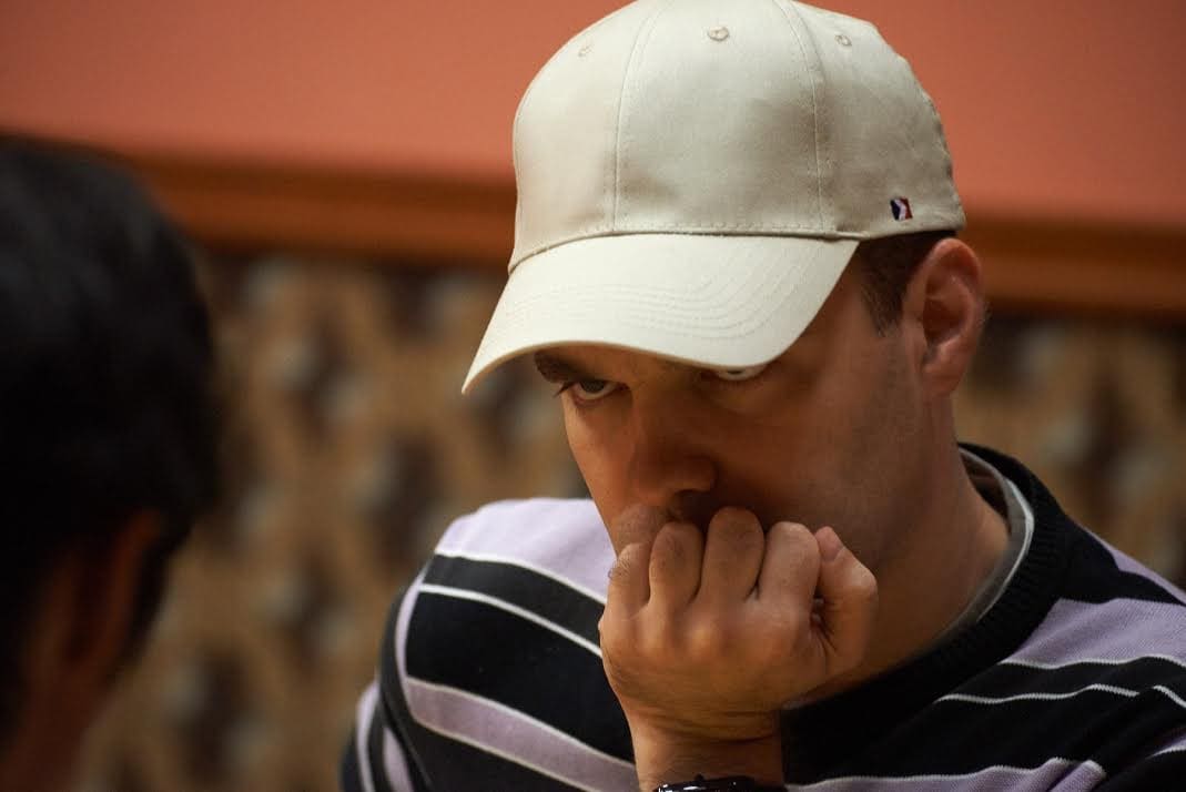 A Go player in a cap contemplating a crucial move during a game.