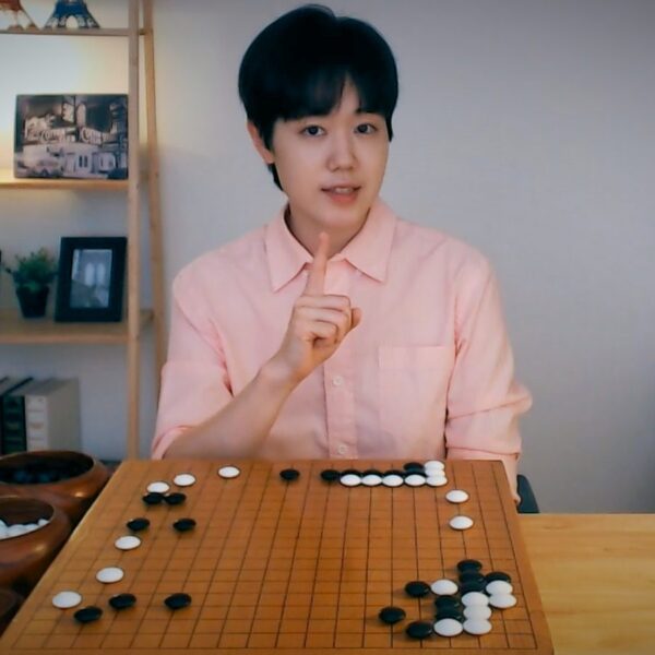 Woman teaching Go with a wooden board and stones at a cozy desk setup
