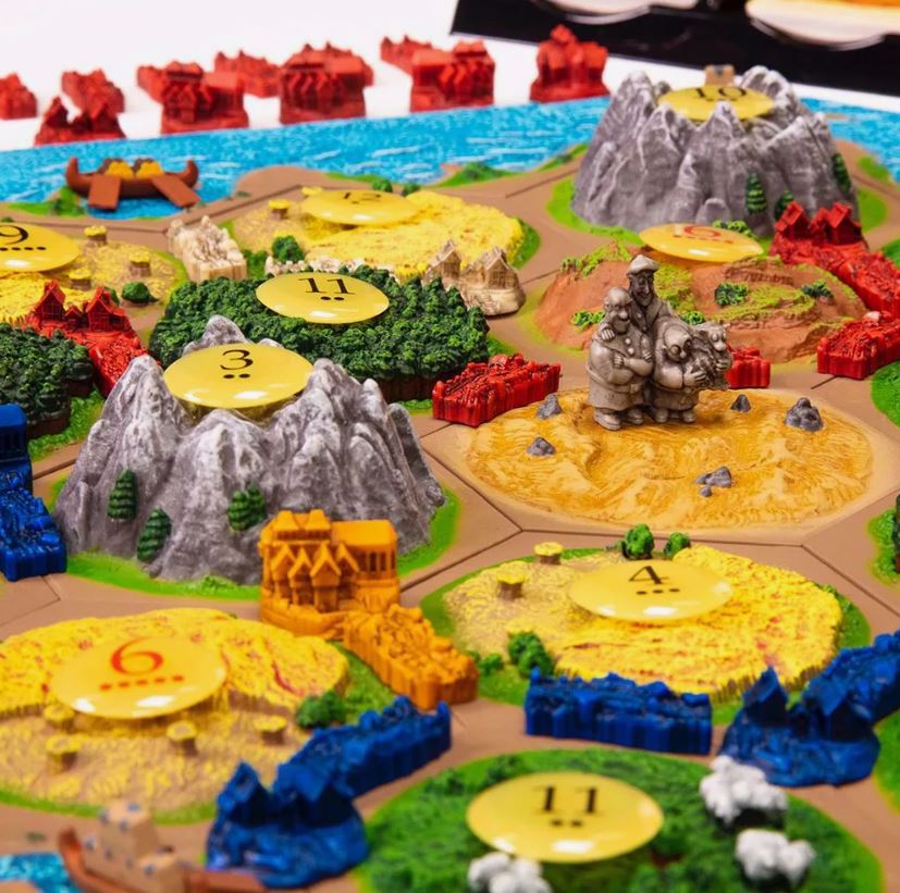 A detailed view of the Settlers of Catan board game showing hexagonal tiles with different terrains and game pieces.