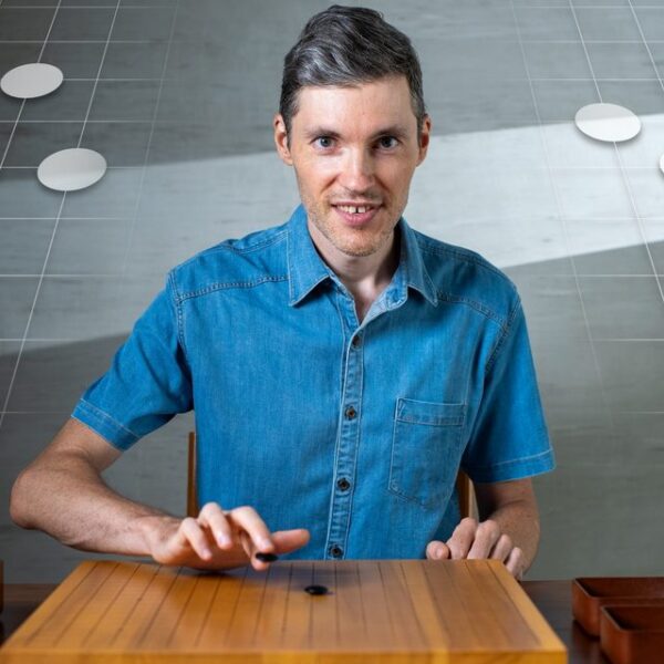 Man playing Go at a wooden board with digital stones floating behind