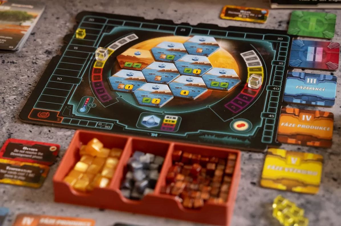 A close-up of the player board and resources from the game Terraforming Mars: Ares Expedition, showing tiles, cubes, and player markers in a space-themed setting.