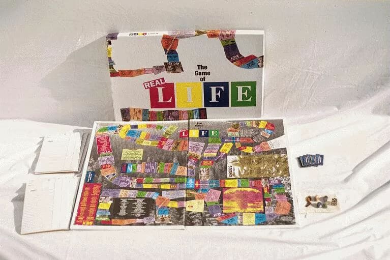 A 1990s edition of The Game of Real Life with a colorful game board, dice, and instruction sheets laid out for play.