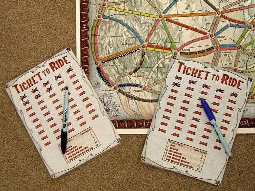 Ticket to Ride score sheets and a game board with colorful railway routes drawn across a map.